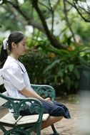 Asian girl sitting on a bench with eyes closed