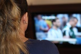 blonde girl watching football on tv