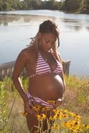 pregnant woman in a bathing suit on a background of a pond