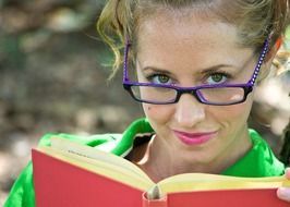 girl in blue glasses reading a book