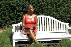 gold sculpture in a woman on a bench