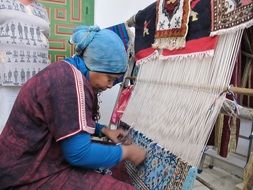 a woman weaves a carpet