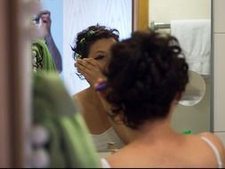 girl puts makeup on her face near the mirror