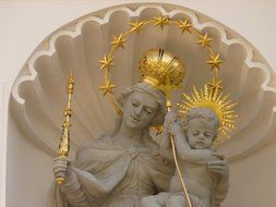 sculpture of a woman with a child in a golden crown with a scepter