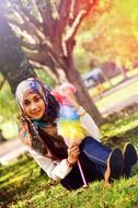 islamic girl sits on lawn in park