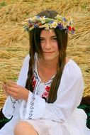 girl in the traditional suit of peasants with a wreath on her head on the background of summer nature