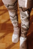 female legs in pantalone and white shoes on parquet floor