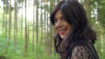 smiling woman in front of forest, portrait