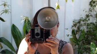 girl taking vintage photo camera at face