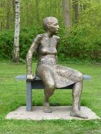 woman sits on bench, modern bronze sculpture in park