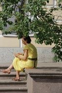 woman in a yellow dress sitting under a tree