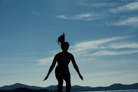 silhouette of jumping girl on landscape background