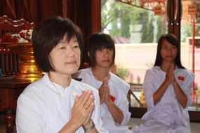 women meditate in a buddhist temple in Thailand