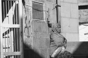 old indian woman sits at wall