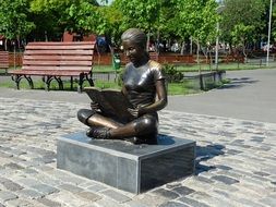 statue of a woman with a book in the park