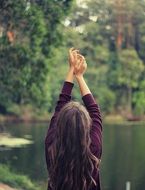 girl posing with arms raised near the lake