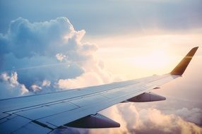 view of an airplane wing and a sunrise with clouds