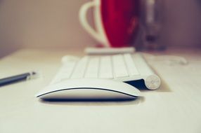 computer mouse keyboard red cup on white table