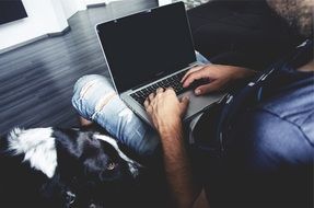 man working on a macbook with his cute dog