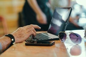 man hand laptop mobile sunglasses table