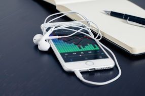 smartphone with earphones and notebook with pen