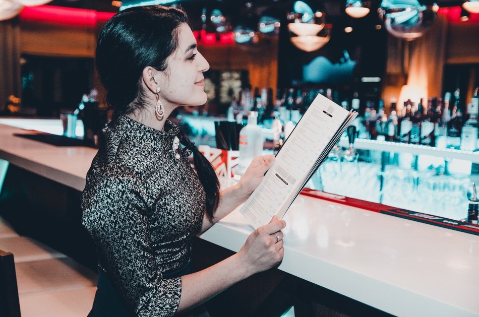 the girl behind the bar with a menu