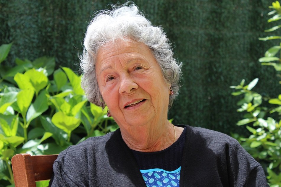 an elderly woman sits on a chair