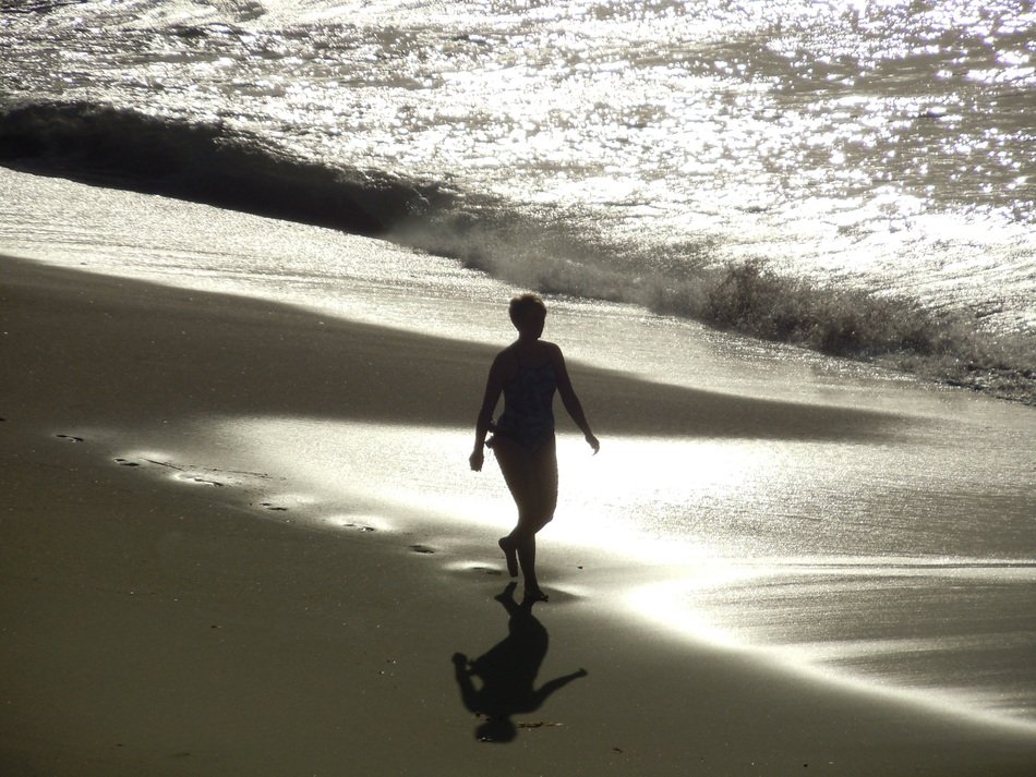Woman is walking on the beach near the water
