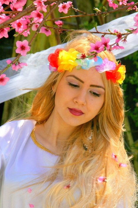 portrait of a beautiful blonde girl on background of blossoming branches of tree
