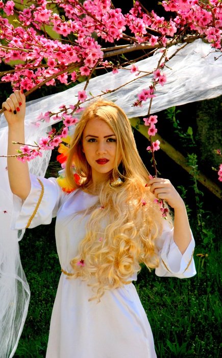 Girl with blond hair on the background of a flowering tree