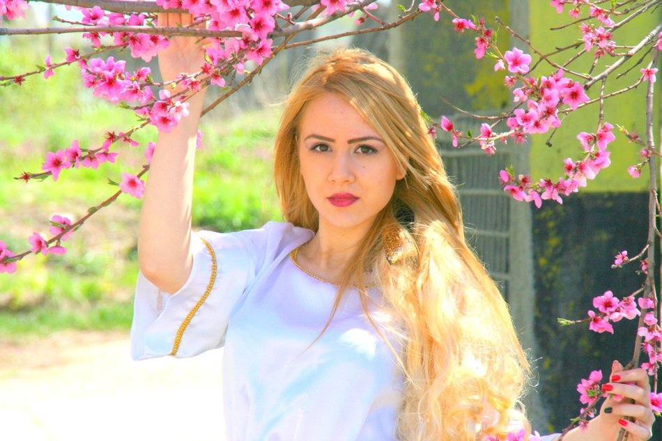 blonde girl on the background of the blossoming branches of tree