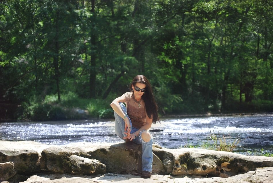 woman sitting on a stone near the river