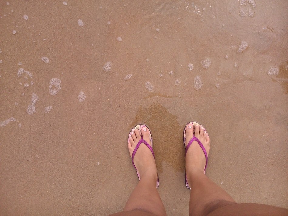 feet in pink flip flopsrs by the water