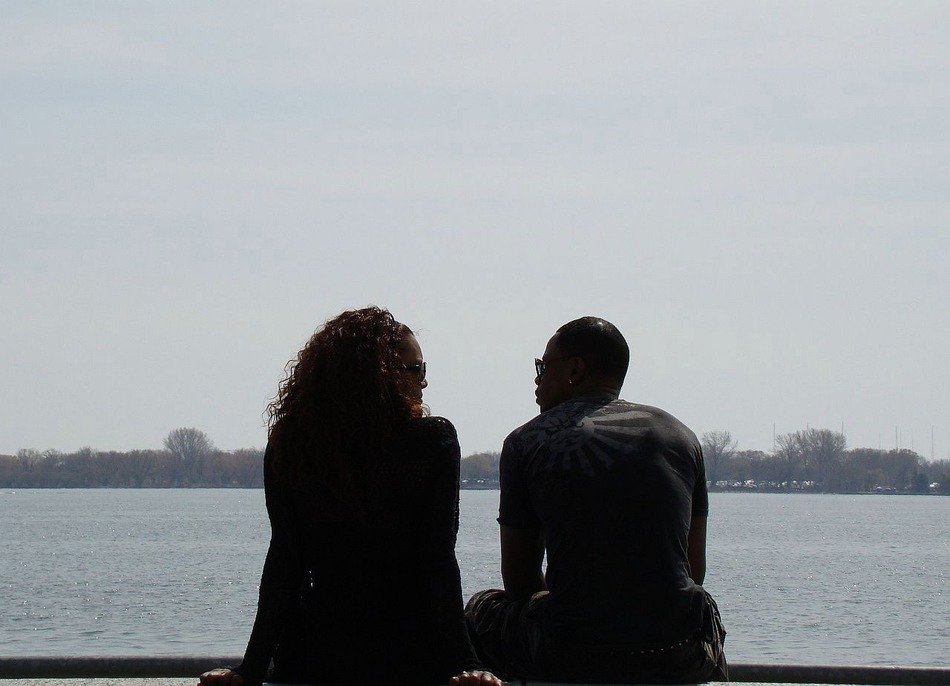 man and woman sitting at lake