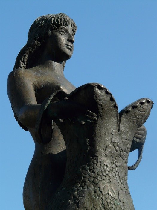 sculpture of graceful girl with the dress in hands