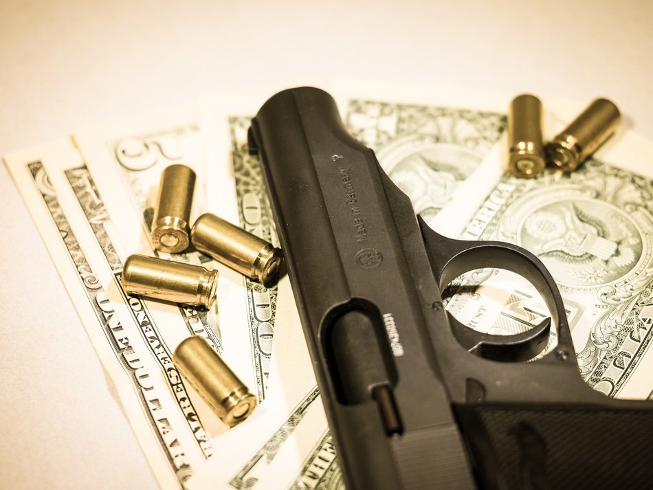 gun with bullets lying on dollar bills