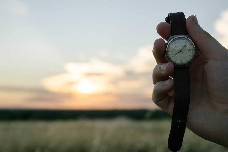 watches in hand field sunset