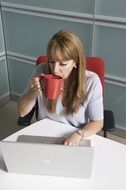 a woman drinks coffee in the office