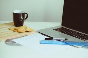 macbook laptop tea and cookies on the table