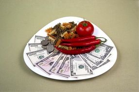 pasta, chili pepper, tomato and dollars on a plate