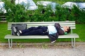 business man sleeping on bench in green park