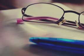 glasses and notepad and pen close-up on blurred background