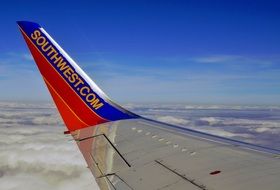 southwest script on planeâs wing above clouds