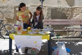 two child girls sell lemonade on the street