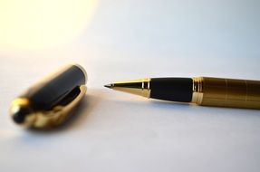 Black and golden pen on the white table