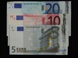 Three different euro banknotes on a black background