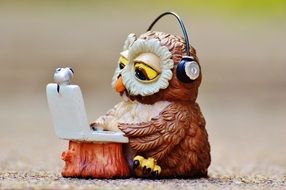 A figure in the shape of an owl that works with a laptop in headphones