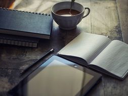 ipad notebooks and a coofee at a workplace