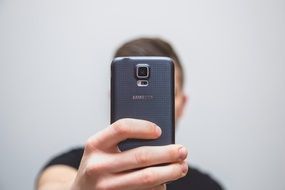 man taking a selfie of a mobile phone