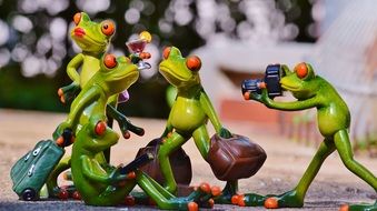 group of toy frogs with luggage and a photographer